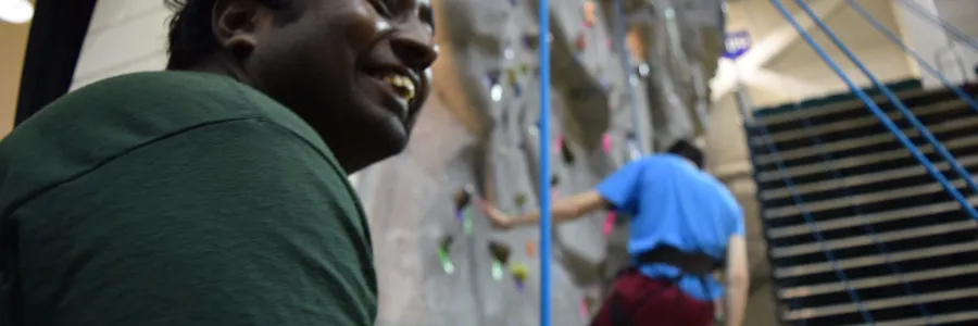 Belayer at the indoor wall while a climber is lowered