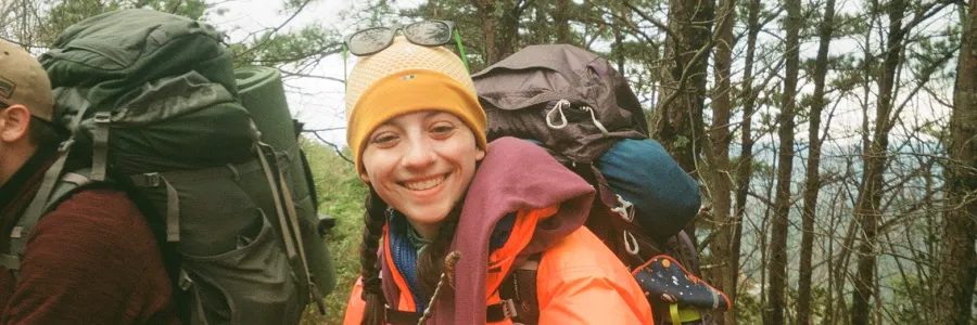 Smiling backpacker holding a clover.