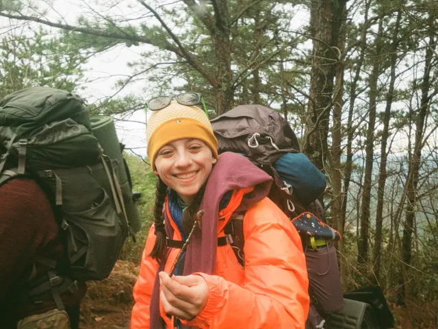 Smiling backpacker holding a clover.