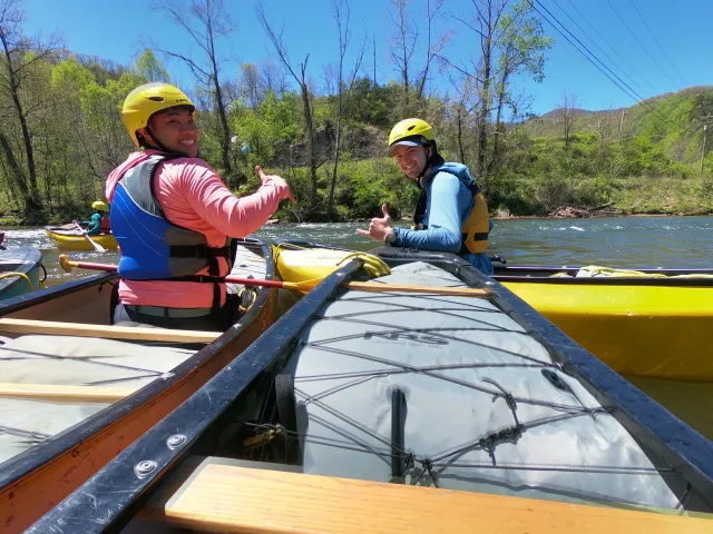 Two whitewater canoers giving a thumbs up